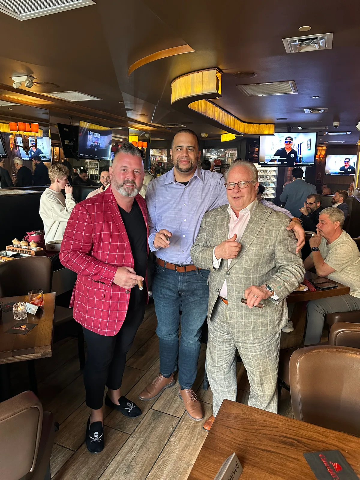 Three guests posing together at a cigar lounge gathering