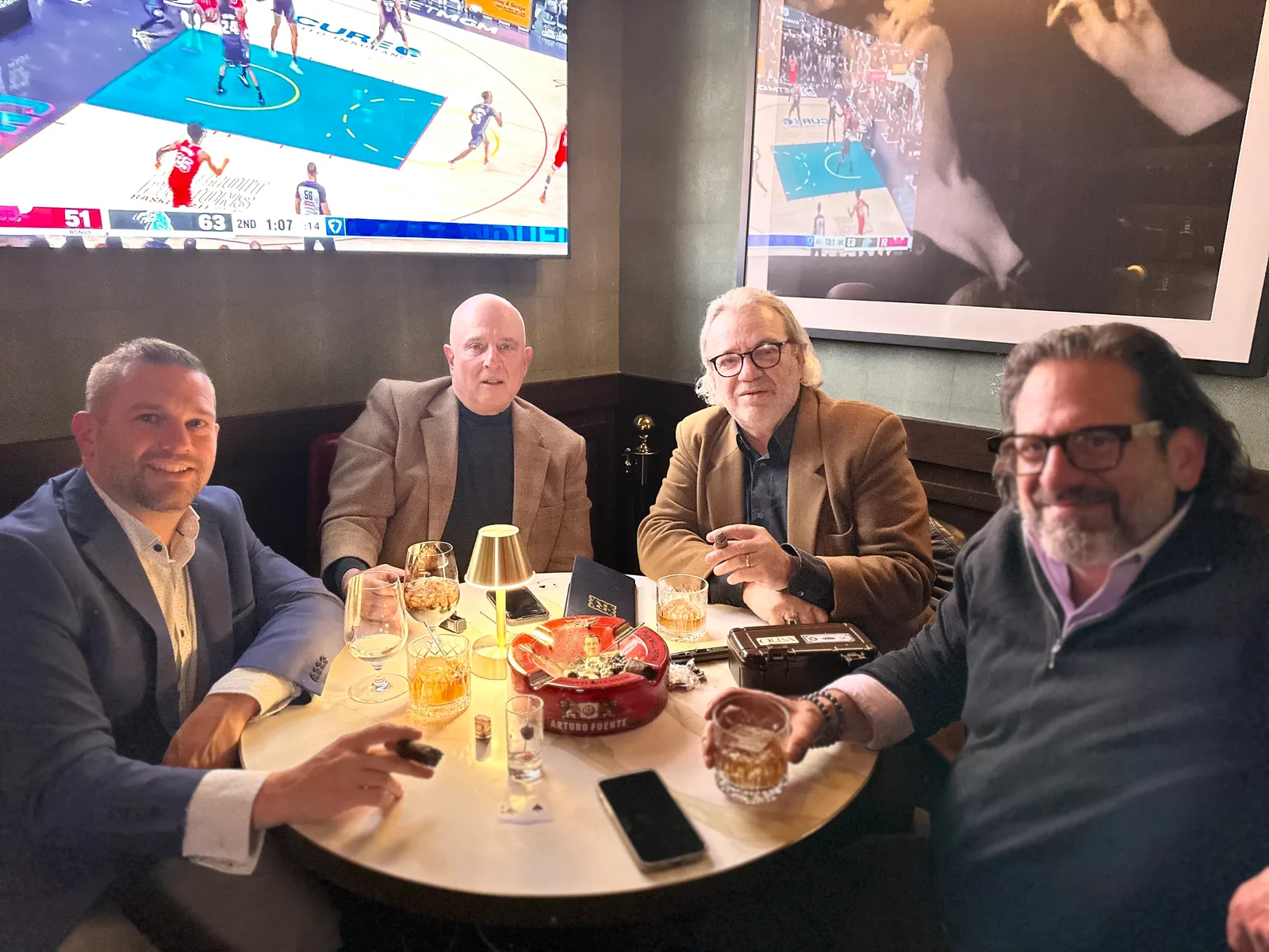 Friends gathered around a table with drinks and cigars