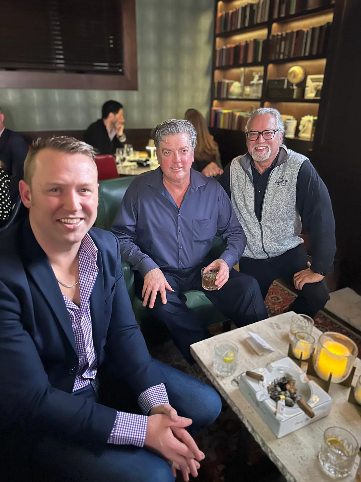 Three friends seated with drinks at a lounge table